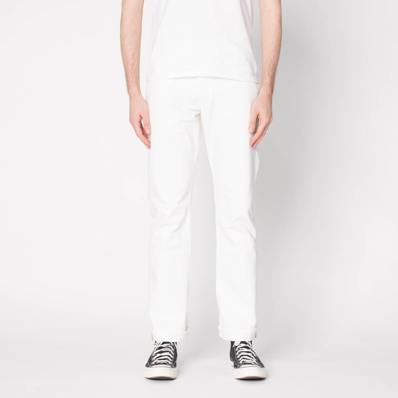 Person wearing white pants and black sneakers on a light gray background