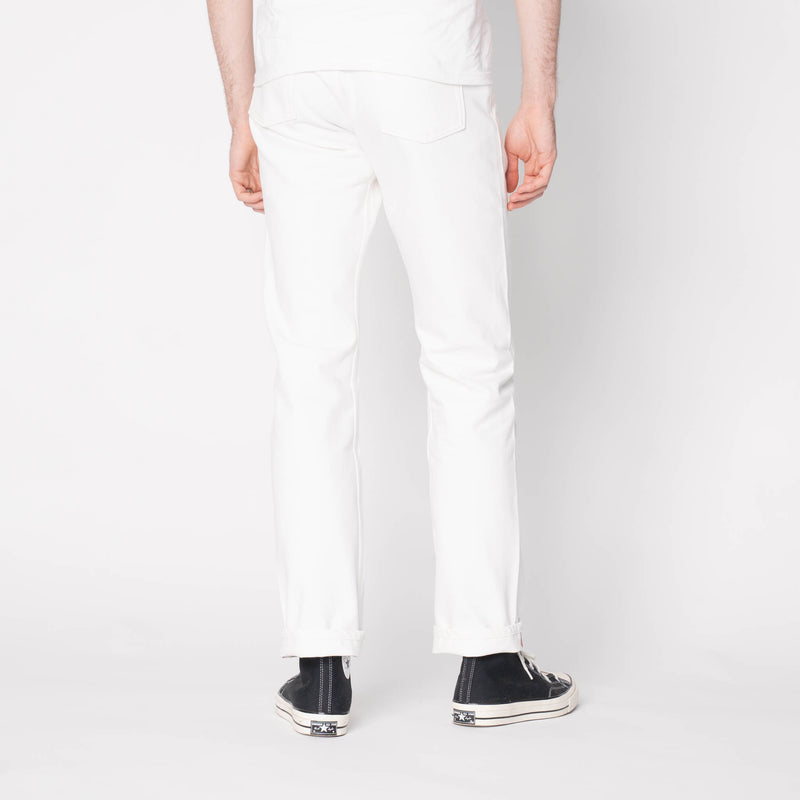 Person wearing white pants and black shoes on a plain background